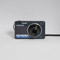 Samsung DV150F blue digital camera — front view with lens extended